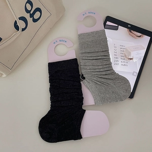 Close-up of grey and black ribbed leg warmers with pink H.T. SOCK tag and canvas bag
