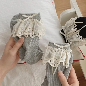 Close-up of ballet style socks with delicate white lace trim and ribbon bow details