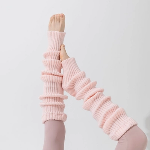 Detail of light pink knit leg warmers with textured ribbed pattern and cozy layered style