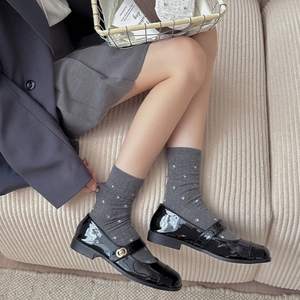 Classic black patent leather Mary Jane shoes paired with gray floral knit mid-calf socks