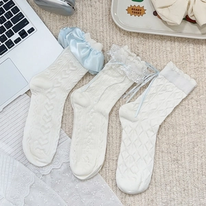 Detail of white Lolita socks with lace frills, blue satin bows and heart-knit textures