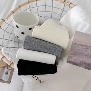 Détail de chaussettes en coton côtelé blanc, gris et noir dans un panier décoratif