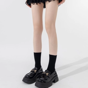Detail of glossy black patent leather loafers with golden metal buckles and thick soles