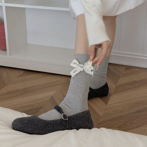 Détail de chaussettes grises à côtes avec nœuds en dentelle blanche et chaussures