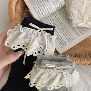 Detail of knit socks featuring elegant white lace trim and delicate ribbon bows