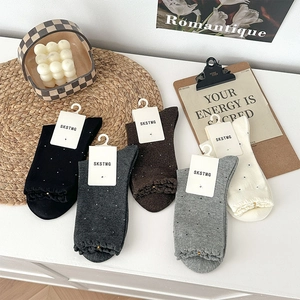Detail view of five-color polka dot socks with elegant ruffle cuffs and paper tags