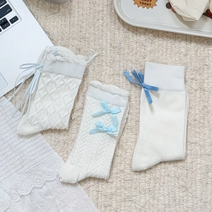 Three-pack white Lolita crew socks with blue bows and varied knit textures on beige background