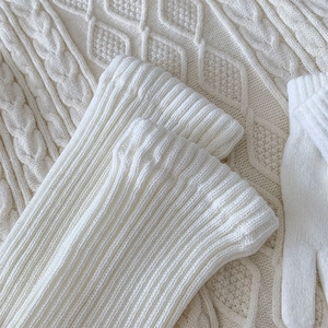 Detailed view of white ribbed knit leg warmers and matching gloves with soft texture
