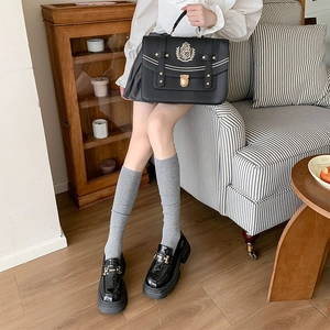 Détail de chaussettes hautes en maille grise avec mocassins noirs et sac vintage rétro
