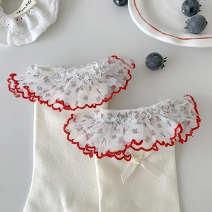 Detail of white cotton socks with red-edged lace trim and silk ribbon bow accent