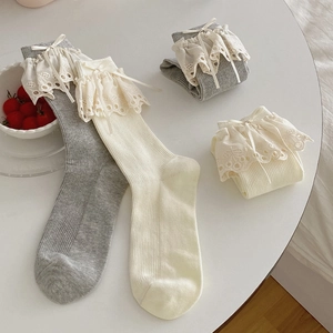 Close-up of ballet style ribbed socks with wide lace trim and silk bow details