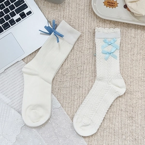 Detail of white Lolita socks with delicate blue silk bows and intricate lace jacquard textures