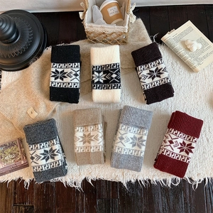 Detailed close-up of chunky knit leg warmers in various colors with snowflake patterns