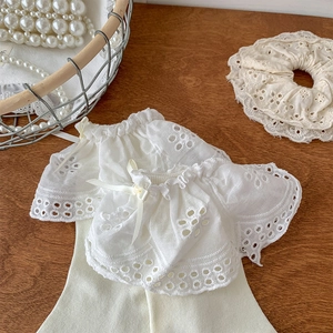 Detail of white Lolita lace socks with yellow ribbon bows and hollow embroidery on wood