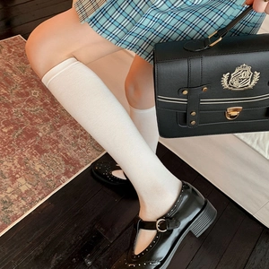 Détail de chaussettes hautes JK blanches avec des chaussures Mary Jane noires vernies