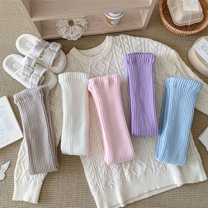 Detail showing various colors of cable knit leg warmers with retro ribbed texture