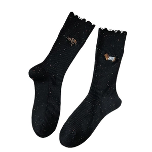 Black knit crew socks with colorful speckles, frilled edges and cute puppy embroidery