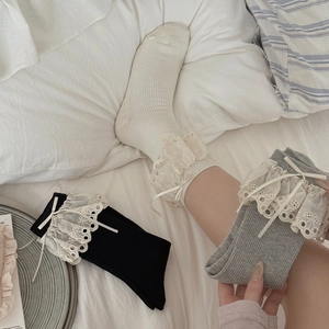 Detail of sweet Lolita mid-calf socks with lace edges and ribbons in white, black and grey