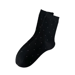 Classic black crew socks with white polka dots and ribbed cuffs on white background
