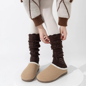 Brown knit leg warmers paired with camel faux suede mules on a white pedestal