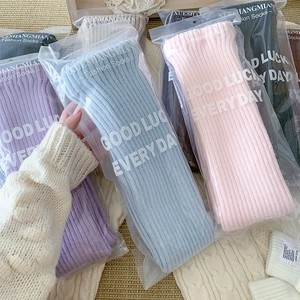 Macro detail of knit ribbed leg warmers in various colors with independent packaging