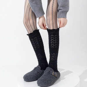 Detail of vintage black hollow-out knitted wool leg warmers with retro lace wave patterns