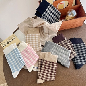 Detailed flat lay of plaid cotton crew socks in various pastel colors on a wooden table