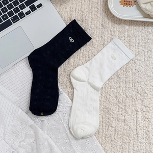 Detail of knit mesh socks with pearl bow accents in black and white styles