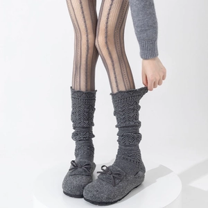 Close-up of grey knit leg warmers with hollow lace patterns and felt bow shoes