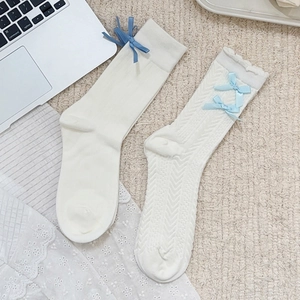 Detail of cream white Lolita socks with blue bows, vertical stripes and cable knit patterns
