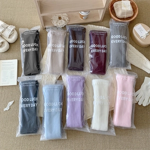 Flat lay of colorful knit leg warmers in 10 colors on a cozy home rug background