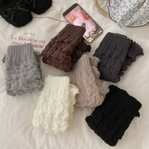Detail of cable knit leg warmers with ruffle edges in various retro neutral colors