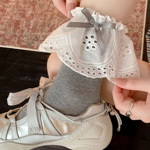 White lace hollow-out ruffled leg warmers with grey bows and metallic silver sneakers