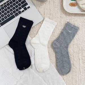 Detail of three pairs of mesh socks with ribbon bows in black, white and grey