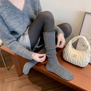 Detail of grey knitted calf socks featuring vintage hollow patterns and slouchy style