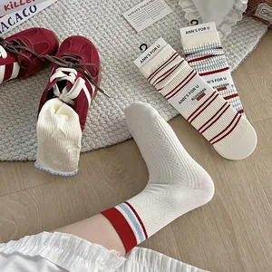 Detail of ribbed cuffs on striped cotton socks with heart lace and retro sneakers