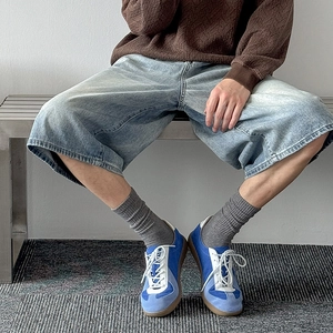 Close-up of blue suede and leather patchwork retro sneakers with gum rubber soles