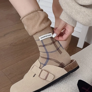Detail of vintage plaid socks in beige with suede clogs on a wooden floor
