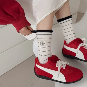 Detail of white cotton crew sock with black stripes and Kikisox animal embroidery label