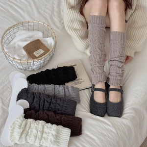 Detailed view of cable knit leg warmers with delicate ruffle trim in neutral tones