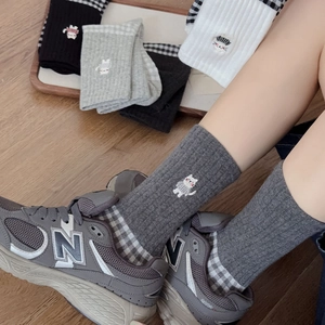 Detail of retro checkered mid-calf socks featuring cute cat embroidery and ribbed cotton texture