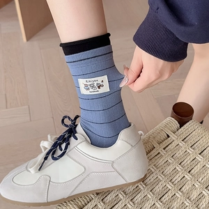 Detail of light blue striped crew socks with cute cartoon bear patch showing high elasticity