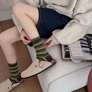 Close-up of retro striped mid-calf socks in dark green and brown with mule shoes