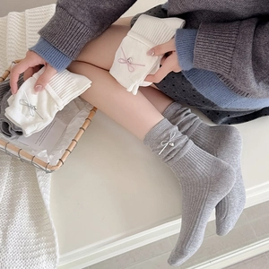 Detail of ballet style knit socks featuring ribbon bows and heart metal pendants