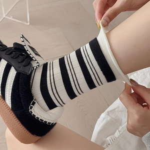 Close-up of black and white striped socks showing the elastic ribbed cuff stretch detail