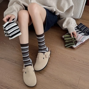 Detail showing striped cotton socks paired with beige suede buckled mule clogs