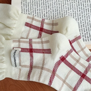 Detail of white knit socks with vintage red plaid patterns and wavy ruffled cuffs