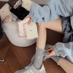 Détail de la broderie cœur et bordure volantée sur des chaussettes en coton multicolores