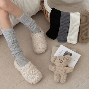 Detailed knit texture of slouchy leg warmers in multiple autumn colors including grey and brown