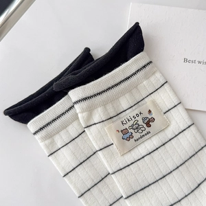 Detail of white cotton socks with black stripes and a cute cartoon bear fabric label